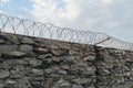 A wall of grey stone topped with barbed wire. Royalty Free Stock Photo