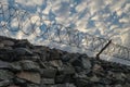 A wall of grey stone topped with barbed wire. Royalty Free Stock Photo