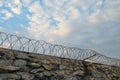 A wall of grey stone topped with barbed wire. Royalty Free Stock Photo