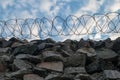 A wall of grey stone topped with barbed wire. Royalty Free Stock Photo
