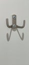 A wall hook designed with a sleek finish is mounted on a white wall. The hooks create interesting shadows, adding a Royalty Free Stock Photo