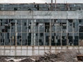 Wall with large broken windows in abandoned ruined factory building, broken glass and destructed old plant facade Royalty Free Stock Photo