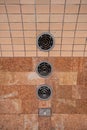 The wall is lined with brown marble and ceramic tiles with round vents