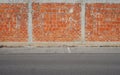 Brick wall with sidewalk and asphalt road in front. Urban background for copy text Royalty Free Stock Photo