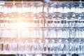 Wall of many empty transparent wine glasses on glass shelf at bar cafe or restaurant against backlit window. Abstract alcoholic