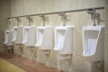 Wall mounted white ceramic toilet in brown tiled bathroom