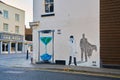Wall Mural of the earth is an hourglass with a doctor wearing a mask by a street corner.