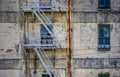 Wall of an old abandoned industrial building with windows and a fire staircase Royalty Free Stock Photo