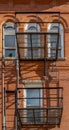 The wall of an old brick building with windows, balconies, and old iron staircase