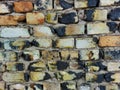 Wall of old burnt bricks of red-brown white yellow black, gray uneven rows close-up Royalty Free Stock Photo
