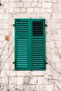 The wall of the old house is white brick with new green shutters. Royalty Free Stock Photo