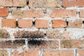 Wall of old orange red cracked brick with a thick layer of cement between them. Some bricks have a black spot Royalty Free Stock Photo