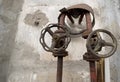 Knobs of old valves installed on old water pipes outside an industrial building.