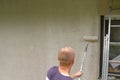 wall painting.Home renovation outside. man paints a wall at house in beige with a roller.Repair work at home.Building