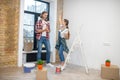 Young couple standing n in the empty room ready to start paintng