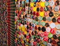 Wall of a pub covered with multicolored caps of beer bottles and drinks