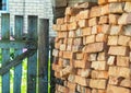 A wall of red and orange bricks stacked in rows outside in the courtyard near an old wooden door. The old brick. building material Royalty Free Stock Photo