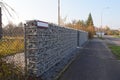 Wall separating the house from the street made of gabions. Autumn