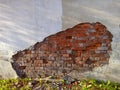 On the outer wall, in the slanting sunlight, behind a large fragment of collapsed white-painted plaster, an old red brick masonry Royalty Free Stock Photo