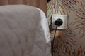 Wall socket with charger plug inside close to bed Royalty Free Stock Photo