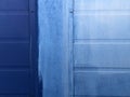 The wall surface is covered by metal wall panels painted in blue. On the surface there are cracks , peeling paint Royalty Free Stock Photo