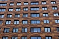 Wall of a trendy modern building with windows with an abstract brown rectangular tile facade. City landscape. Royalty Free Stock Photo