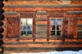 Wall with two Windows of wooden houses from round logs. Winter. The Museum of wooden architecture under the open sky. Russia, Sibe