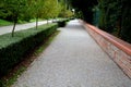 Wall with an upper edge made of atypical rounded fired bricks. Street with a wide cobblestone sidewalk and a shaped hedge with an Royalty Free Stock Photo