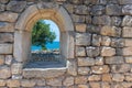 Wall with a window in the ruins of the ancient city with a view of the sea, a tree and people, selective focus Royalty Free Stock Photo