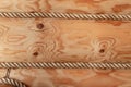 Wall of a wooden log house decorated with decorative rope. Wooden texture closeup Royalty Free Stock Photo