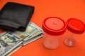 Wallet, dollar bills and medical plastic containers for tests on bright orange background.Payment for medical tests.Selective focu Royalty Free Stock Photo