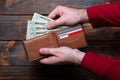 Wallet with dollars in men`s hands. Wallet with money and credit cards on a wooden background Royalty Free Stock Photo