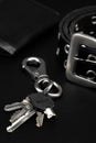 Wallet, keys and leather belt on black background, men accessories concept