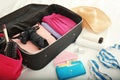 Wallet and open suitcase with packed things on bed Royalty Free Stock Photo