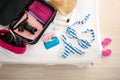 Wallet, swimsuit and open suitcase with packed things on bed, top view Royalty Free Stock Photo