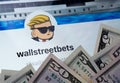 Wallstreetbets Reddit community web page seen on the tablet screen surrounded by US dollars. Concept for investment.