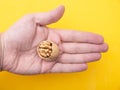 Walnut with a broken shell in the palm of a man on a yellow background, close-up. Concept of the benefits of nuts for