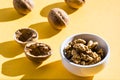Walnut kernels in a bowl and walnut shells on a yellow table Royalty Free Stock Photo