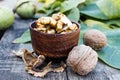 Walnut kernels lie in a bowl next to nuts in green shells and green leaves on a rustic old wooden table Royalty Free Stock Photo