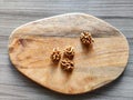 Walnut kernels on wooden cutting board of arbitrary shape on the background of gray table surface. Top view. Close-up. Copy space Royalty Free Stock Photo