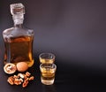 Walnut liqueur, strong homemade alcohol and a handful of nuts on a black background