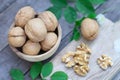 Walnut nut in wooden bowl on wood table with green leaf background, copy space Royalty Free Stock Photo