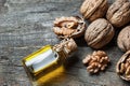 Walnut oil in glass of bottle, whole big peeled walnut kernel with thin shell on wooden background Royalty Free Stock Photo