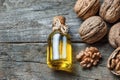 Walnut oil in glass of bottle, whole big peeled walnut kernel with thin shell on wooden background Royalty Free Stock Photo
