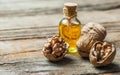 Walnut oil in glass of bottle, whole big peeled walnut kernel with thin shell on wooden background Royalty Free Stock Photo