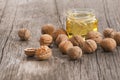 Walnut oil in glass of bottle, whole big peeled walnut kernel with thin shell on wooden background Royalty Free Stock Photo