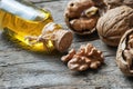 Walnut oil in glass of bottle, whole big peeled walnut kernel with thin shell on wooden background Royalty Free Stock Photo