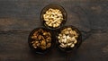 Walnut, pistachio and cashew in a small plates which standing on a black table. Nuts is a healthy vegetarian protein and