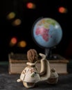 A walnut resting on a miniature scooter with a globe on a book in the background and bokeh of colored fairy lights