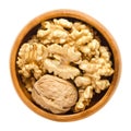Walnut and shelled walnut kernel halves in wooden bowl
